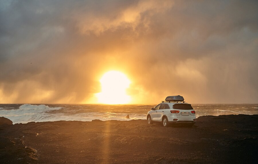 Sunset seaside view of a wind chill pearl colored car