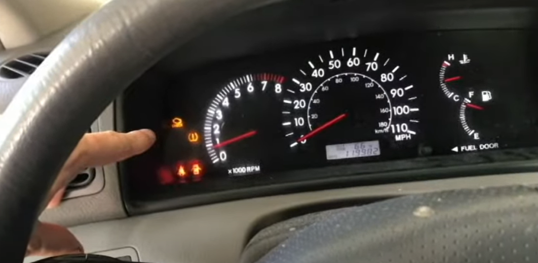 Hand pointing at the 'Check Engine Light' of a car