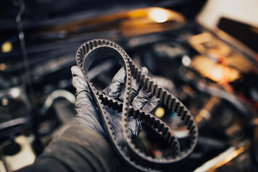 Hand wearing gloves holding car timing belt